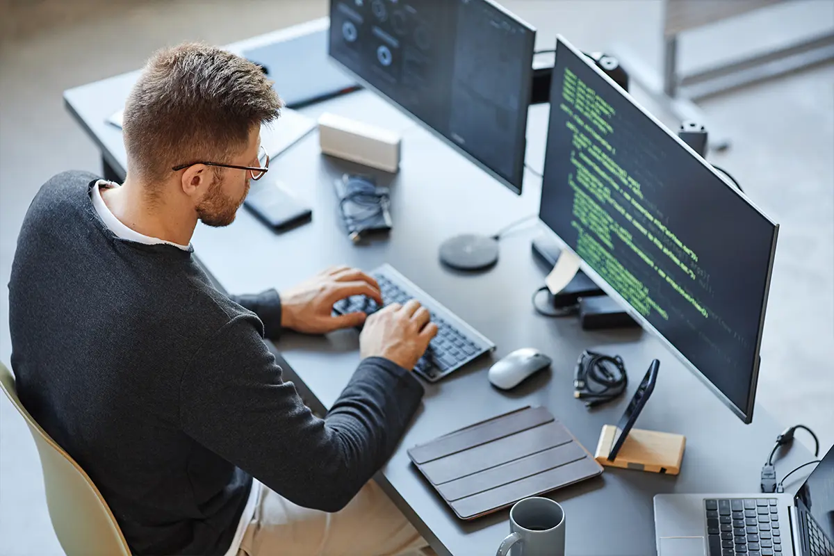 IT-Spezialist programmiert an einem Arbeitsplatz mit mehreren Monitoren