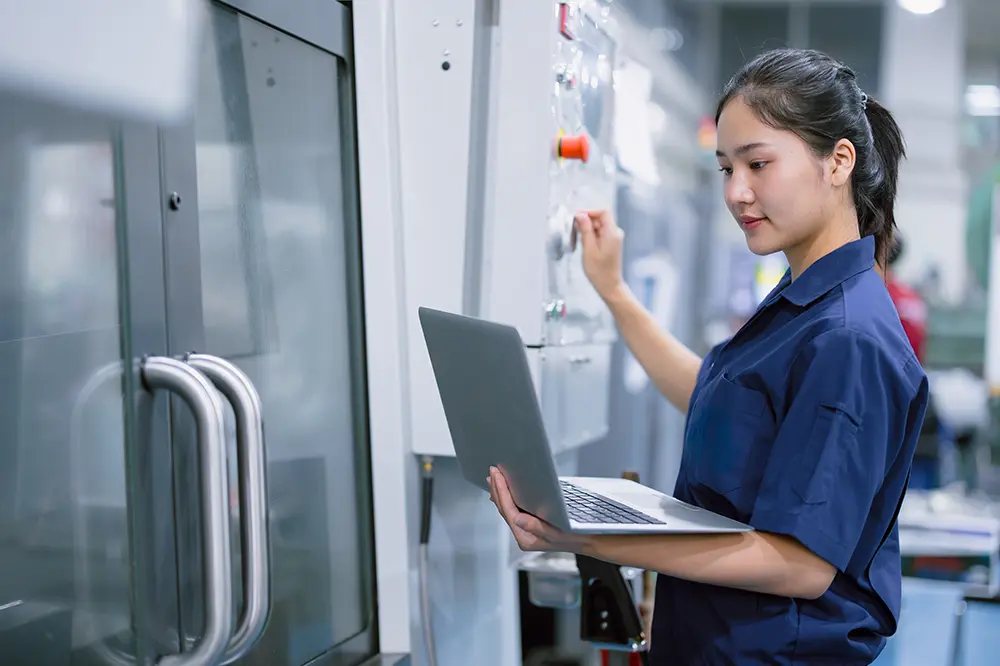 Technikerin mit Laptop an einer Industriemaschine