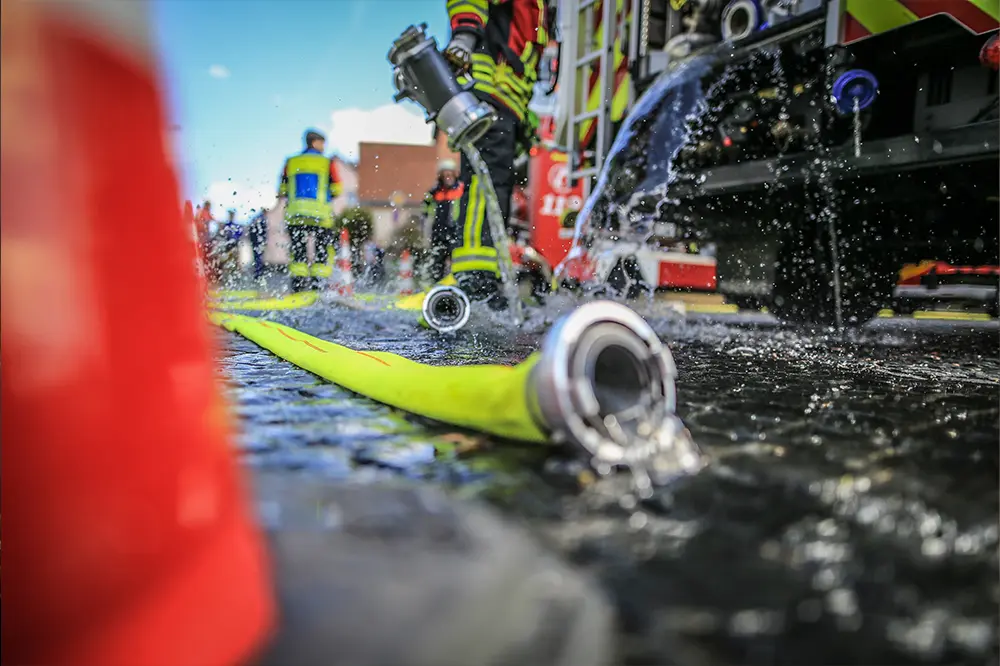 Feuerwehrleute im Einsatz mit einem Löschschlauch
