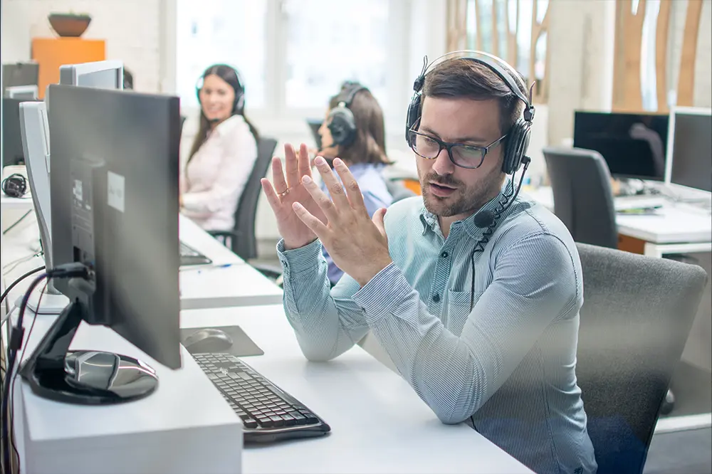 Helpdesk-Mitarbeiter mit Headset erklärt am Bildschirmarbeitsplatz