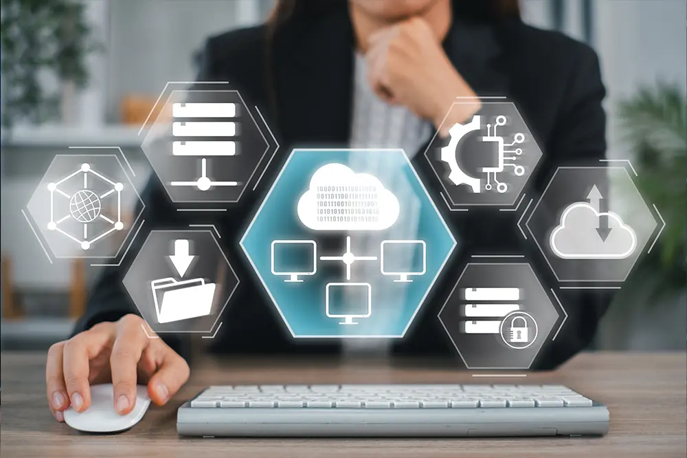 Person am Schreibtisch, davor eingeblendete Symbole für Cloud, Server und Netzwerk
